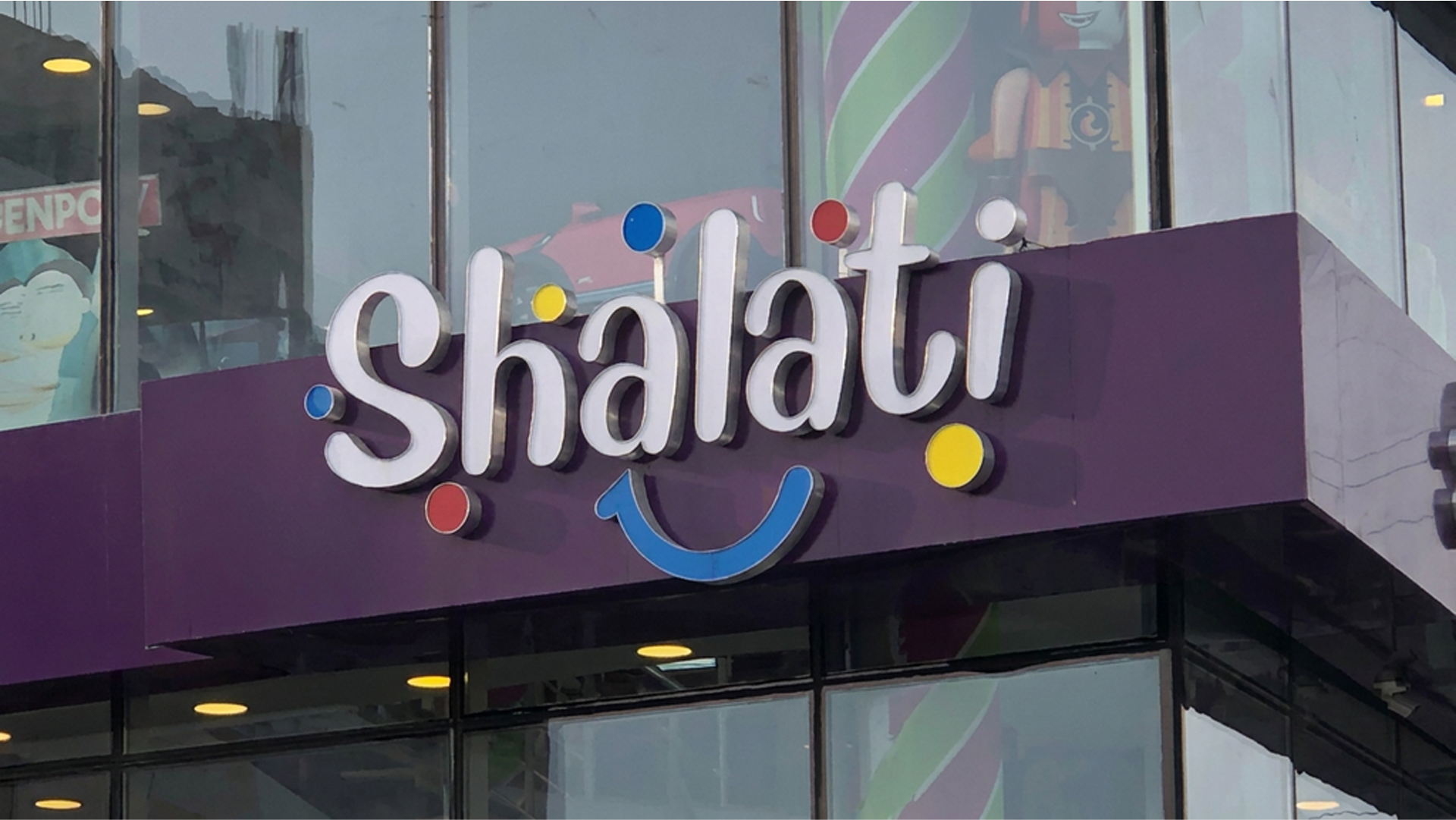 Shalati storefront sign: white wordmark with a blue smile and coloured dots on a purple fascia